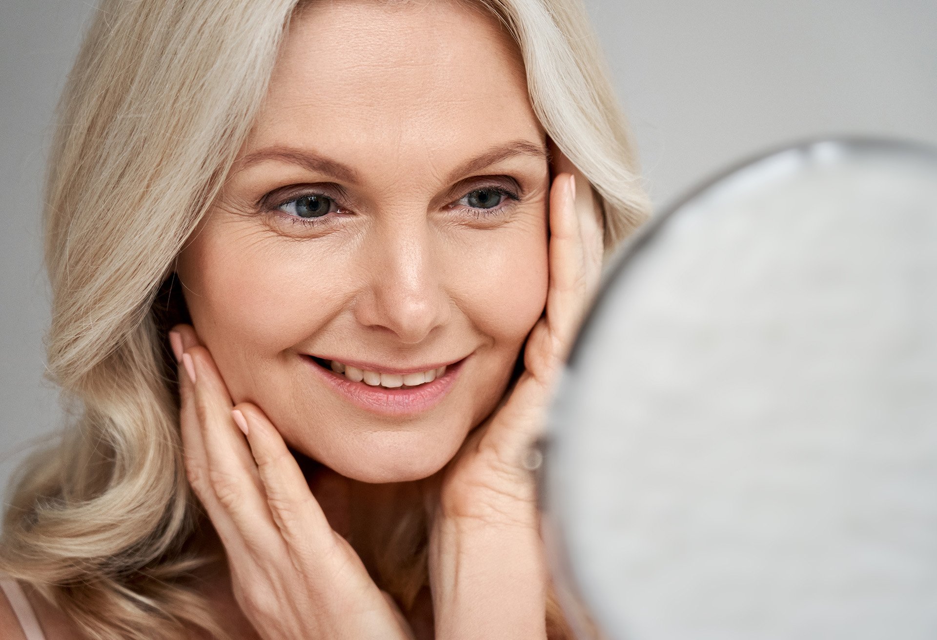 Woman looking into a mirror and smiling